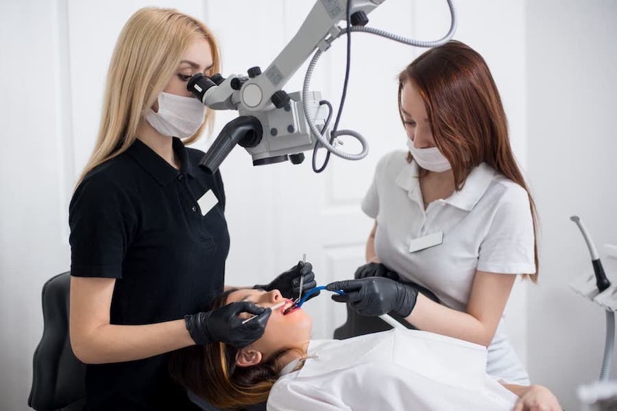 two-female-dentists-and-endodontist-performing-root-canal-treatment-in-los-angeles-using-specialized-microscope-and-top-of-the-line-tools